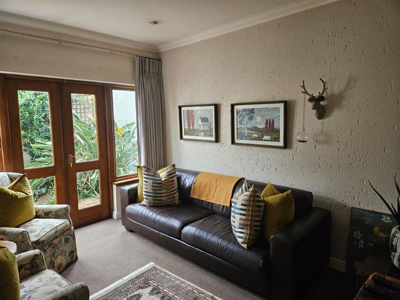 A cozy living room featuring textured walls, coving, and timber-framed glass doors providing natural light and access to the garden.