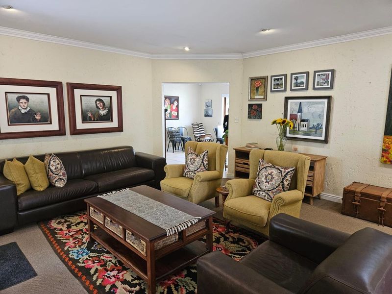 A comfortable living room featuring recessed downlights, coving, and carpeted flooring, with an open transition to an adjacent room.
