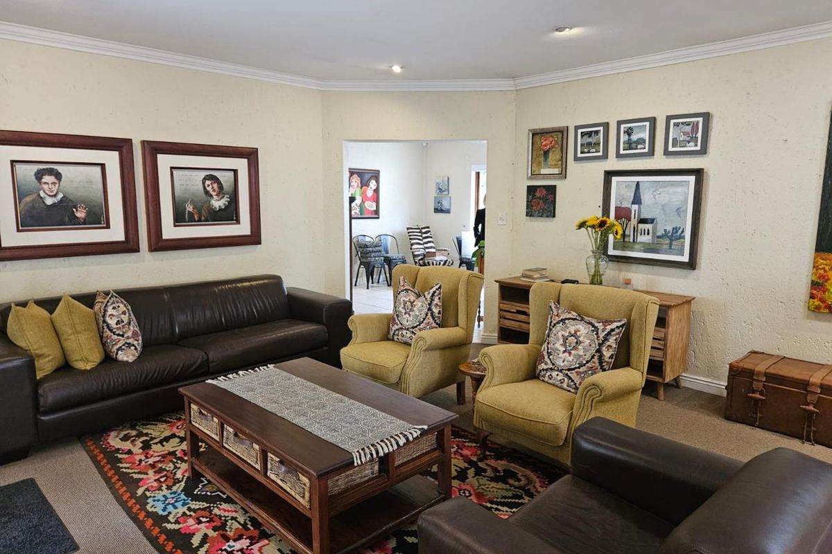A comfortable living room featuring recessed downlights, coving, and carpeted flooring, with an open transition to an adjacent room.