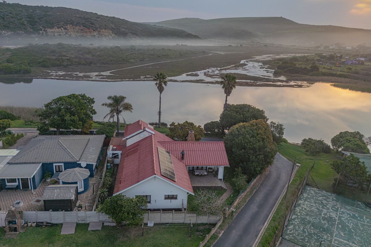 Aerial view of a residential property featuring a metal roof with solar panels, a private tennis court, and scenic views of the adjacent river.