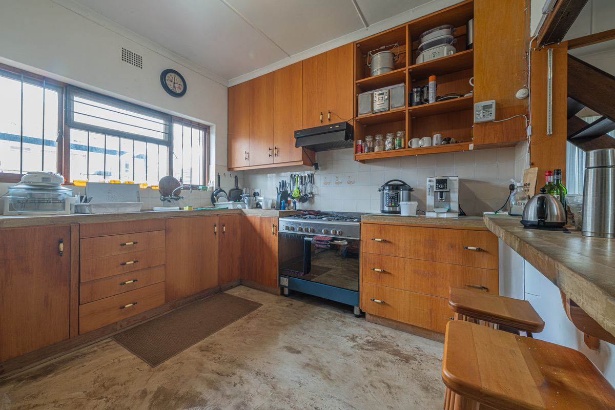 A functional kitchen featuring wooden cabinetry, a built-in oven with gas hob, and a tiled backsplash, offering potential for modernization.