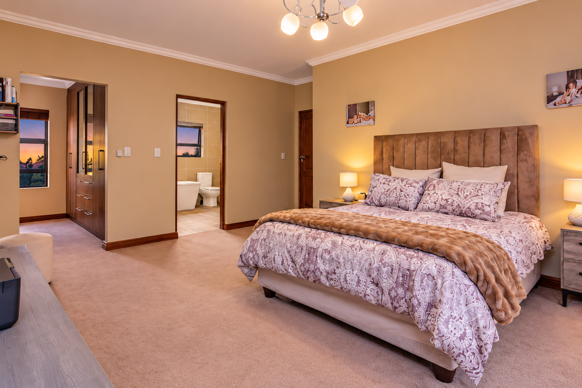 Spacious master bedroom featuring neutral walls, plush carpeting, built-in cabinetry, and an adjoining en-suite bathroom with a soaking tub.