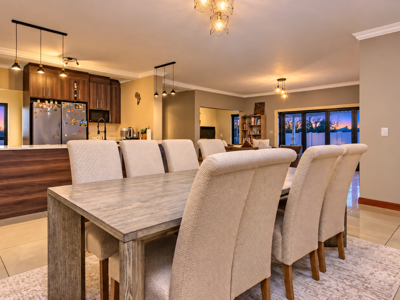 Spacious open-plan living and dining area featuring a modern kitchen with island, tiled floors, and large sliding doors leading to the exterior.