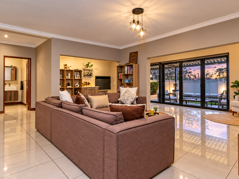 Spacious open-plan living area featuring polished tile flooring, recessed shelving, and large sliding glass doors that provide seamless access to the outdoor patio.