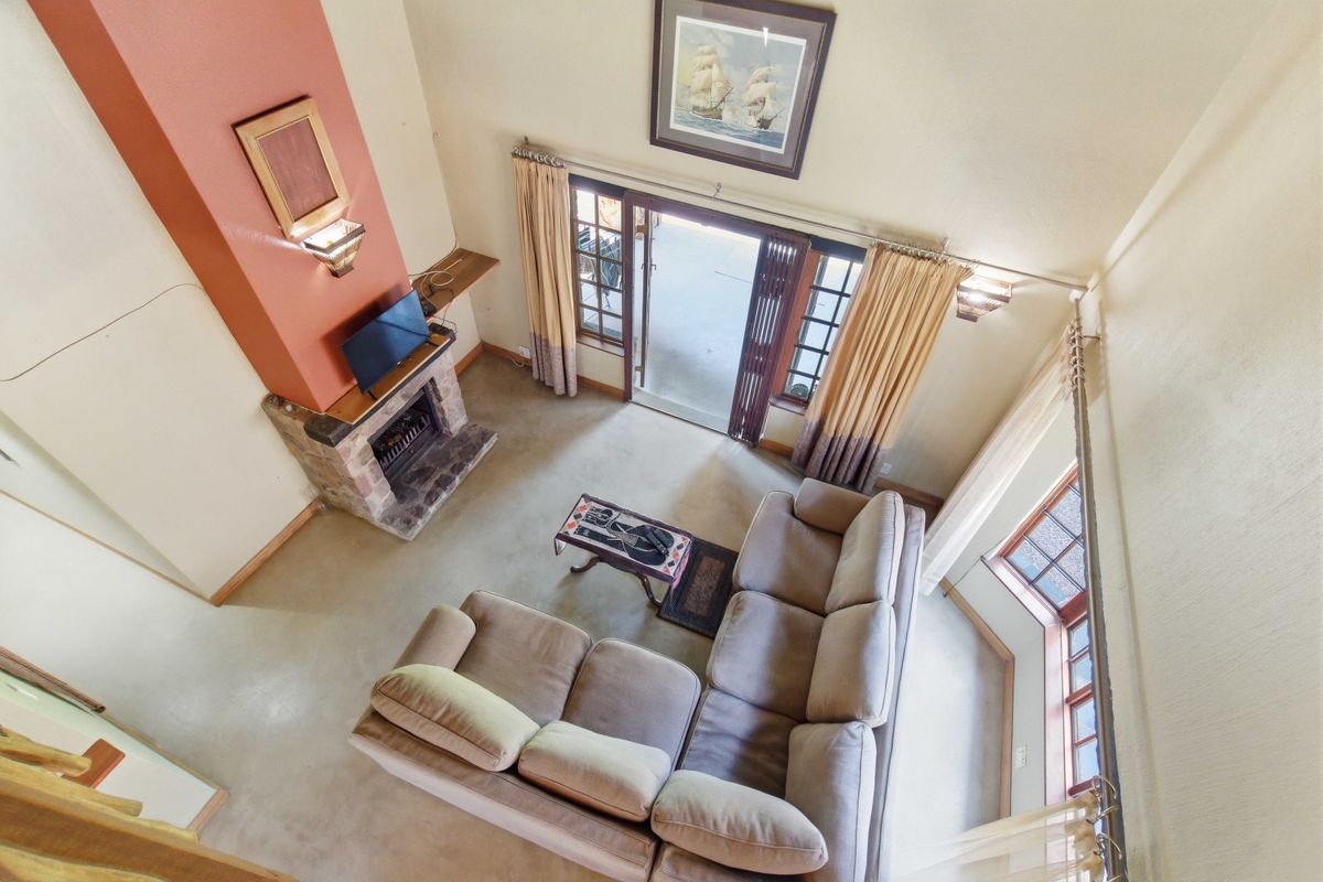 Spacious double-volume living room featuring a stone fireplace, high ceilings, and large sliding doors providing direct access to the outdoor patio area.