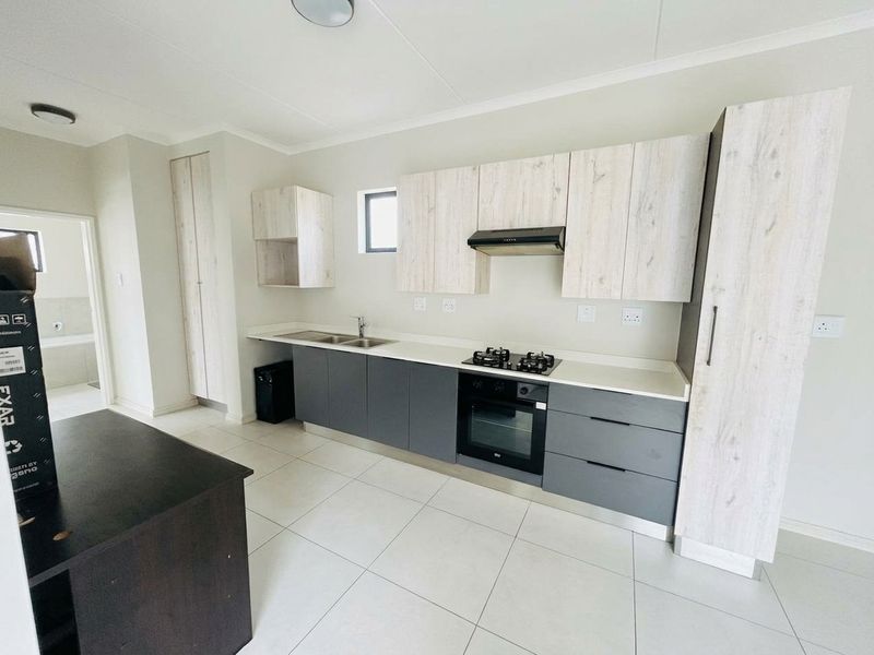Modern kitchen featuring two-tone cabinetry, stone countertops, built-in oven, gas hob, extractor fan, and tiled flooring in a clean, contemporary layout.