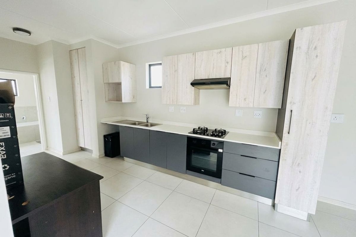 Modern kitchen featuring two-tone cabinetry, stone countertops, built-in oven, gas hob, extractor fan, and tiled flooring in a clean, contemporary layout.