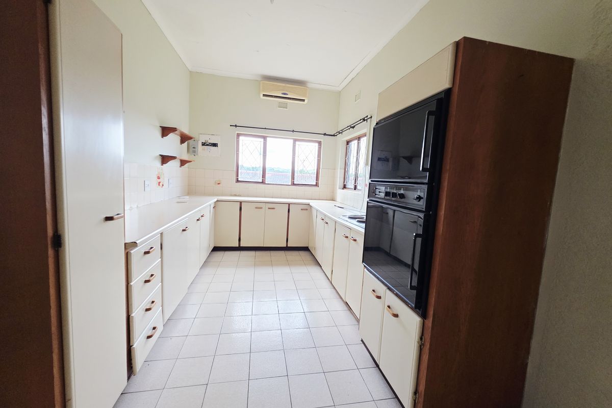 A functional, empty kitchen featuring tiled flooring, ample built-in cabinetry, and a built-in double wall oven, offering a blank canvas for modern updates.