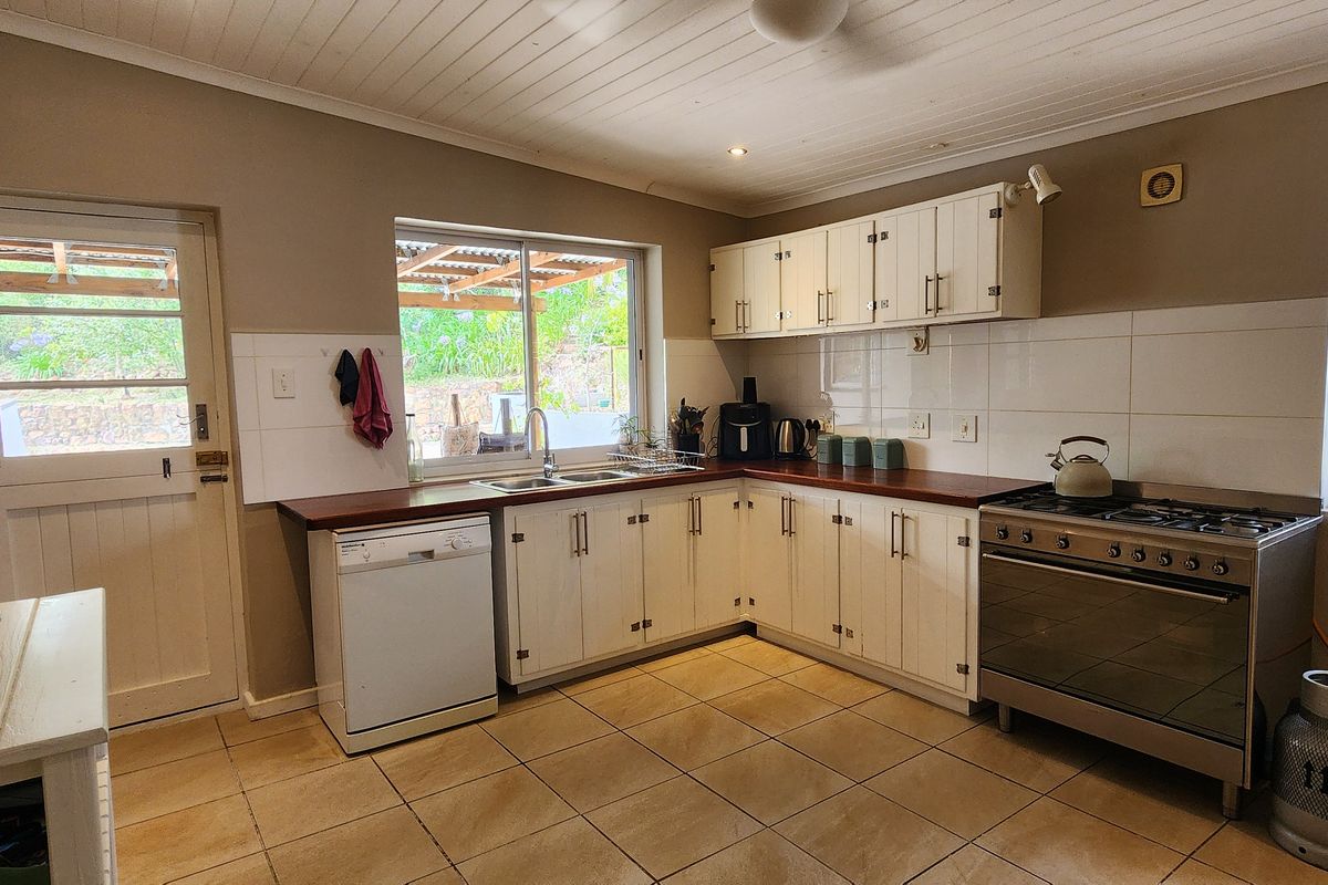 Functional kitchen featuring white cabinetry, timber countertops, gas stove, and tiled flooring with direct access to the outdoor area.