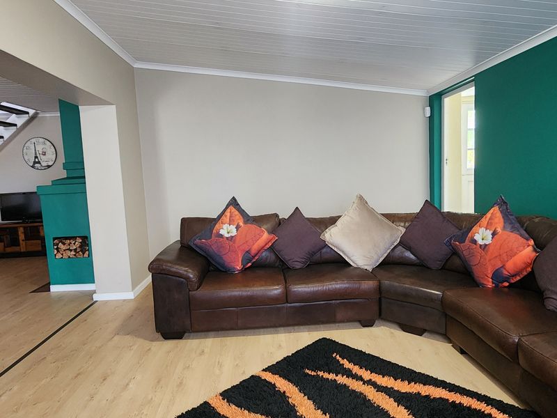 Spacious living room featuring laminate flooring, a built-in fireplace, and an open staircase leading to the upper level.
