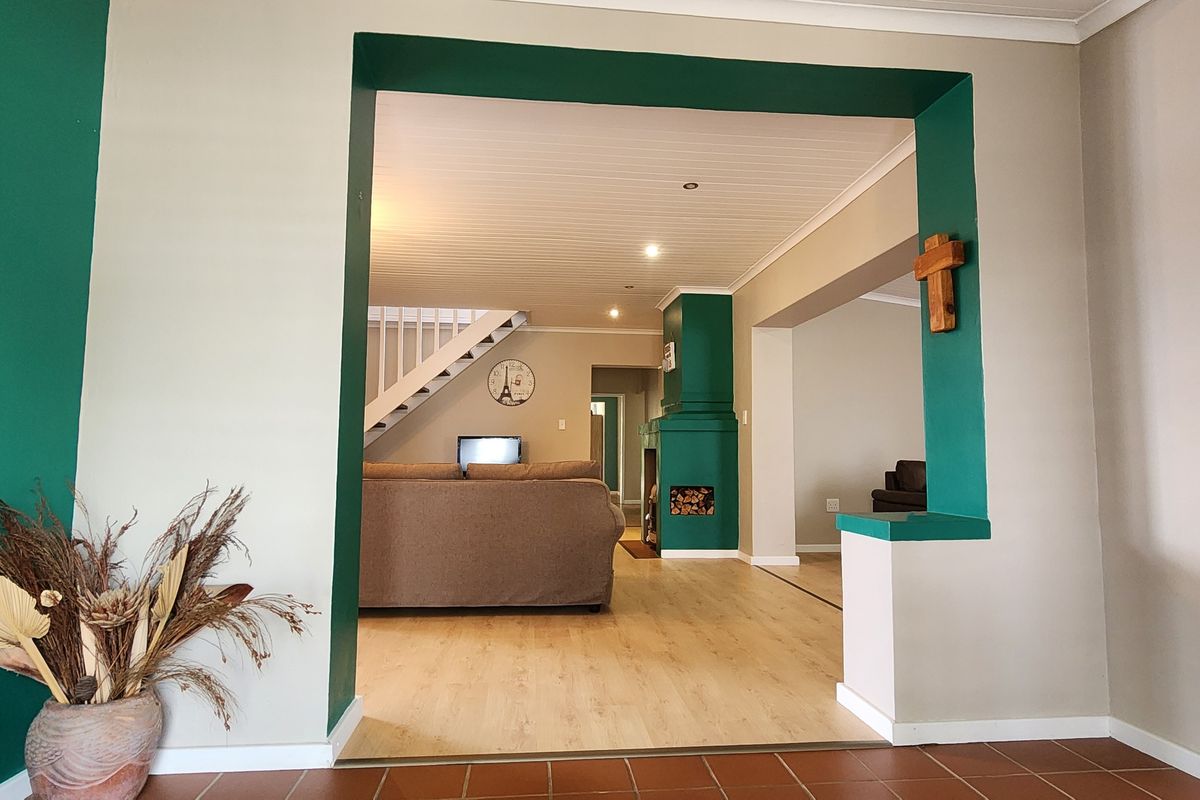 Spacious living area featuring a fireplace, staircase, and a mix of tiled and laminate flooring, offering an open-plan layout with recessed lighting.
