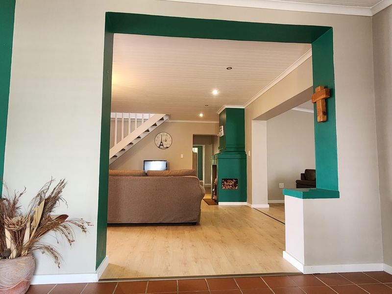 Spacious living area featuring a fireplace, staircase, and a mix of tiled and laminate flooring, offering an open-plan layout with recessed lighting.