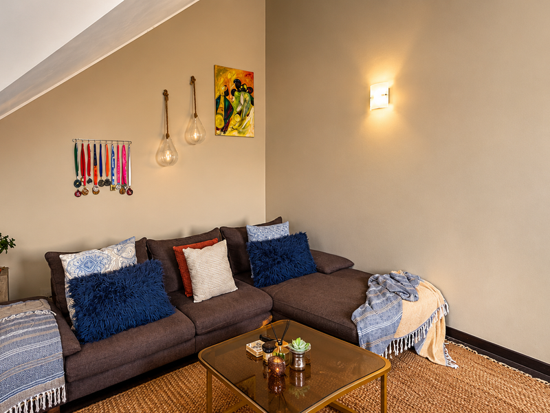 A cozy living room area featuring a sloped ceiling and warm wall-mounted lighting, creating a comfortable and inviting atmosphere.