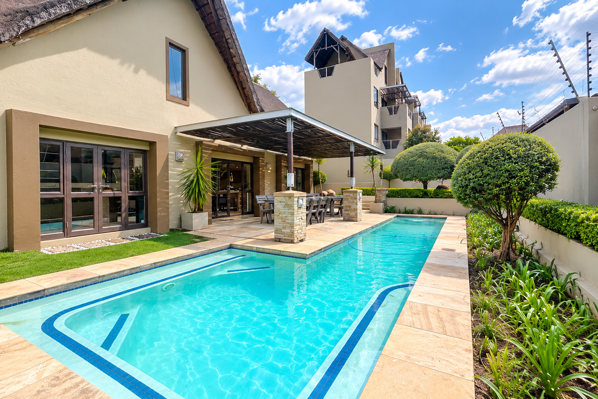 A well-maintained outdoor pool area featuring a sparkling swimming pool, stone-clad patio pillars, and a beautifully landscaped garden with electric perimeter fencing.