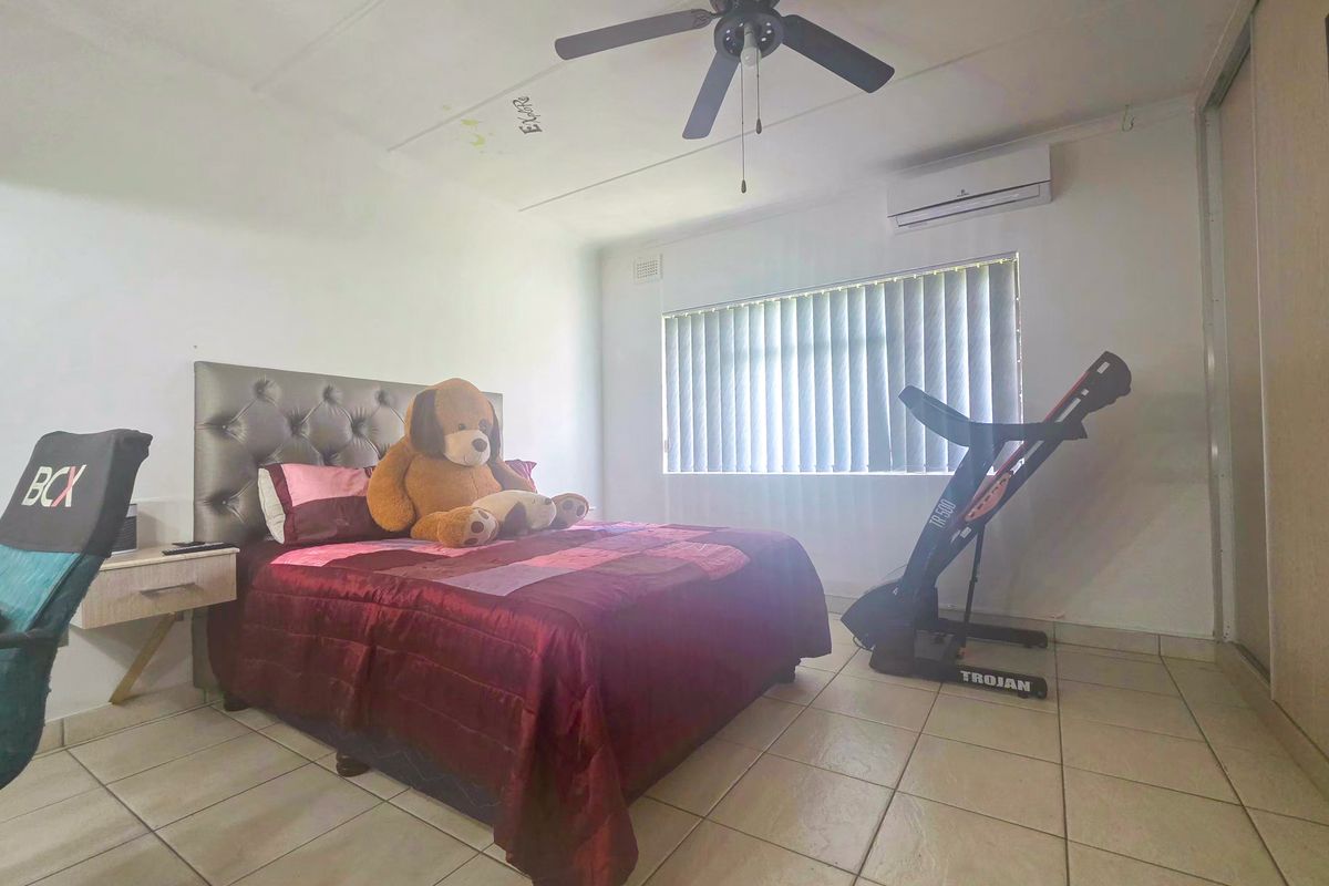 A bedroom featuring tiled flooring, a ceiling fan, a split-system air conditioner, and built-in wardrobe storage.