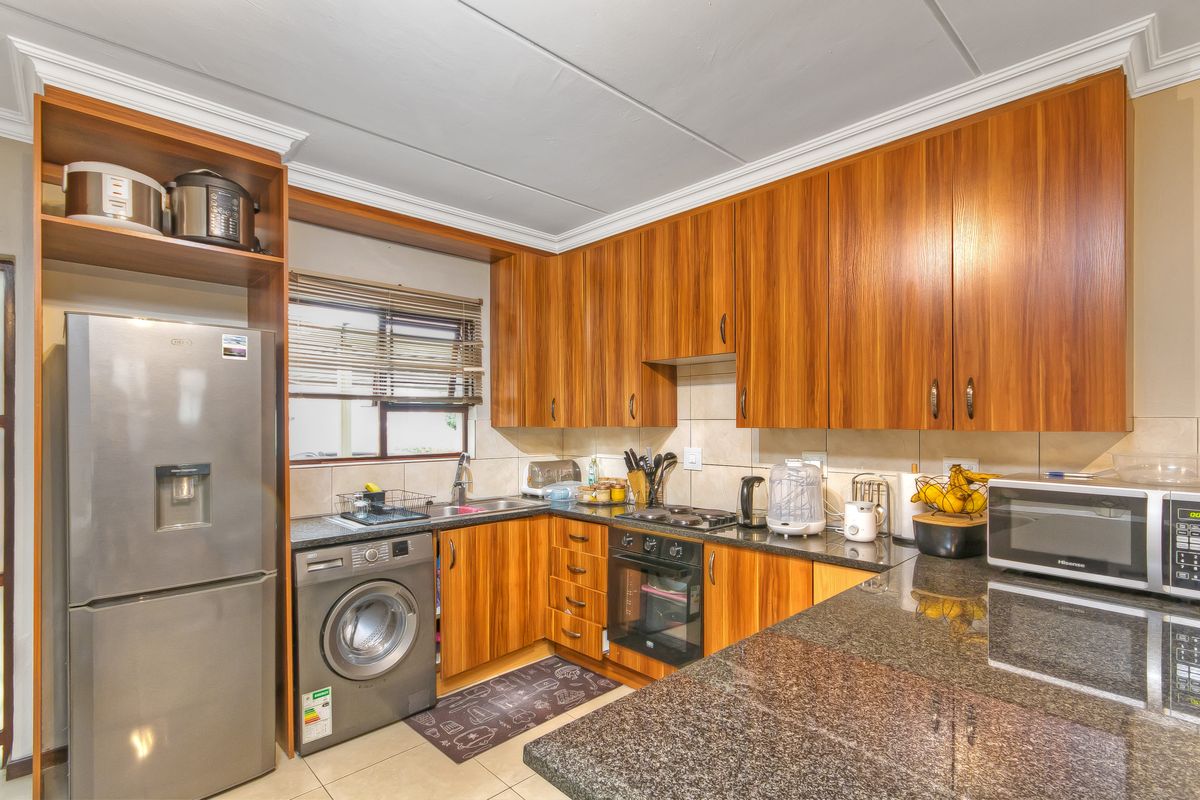 A functional kitchen featuring wood-finish cabinetry, granite countertops, a built-in oven, and a tiled backsplash, providing a practical workspace for daily cooking.