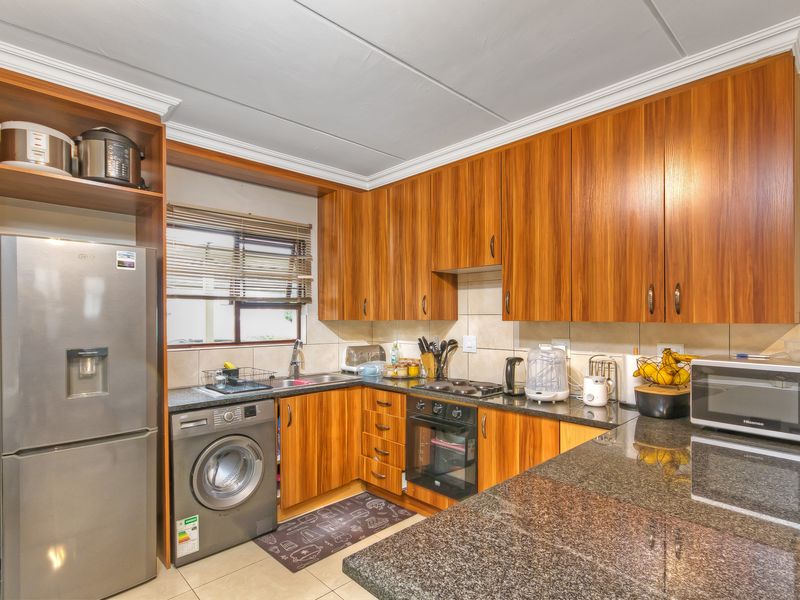 A functional kitchen featuring wood-finish cabinetry, granite countertops, a built-in oven, and a tiled backsplash, providing a practical workspace for daily cooking.