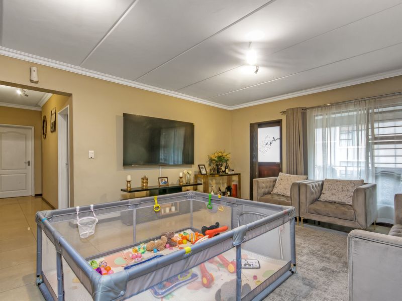 A comfortable living room featuring tiled flooring, coved ceilings, and direct access to an outdoor area through a sliding glass door.