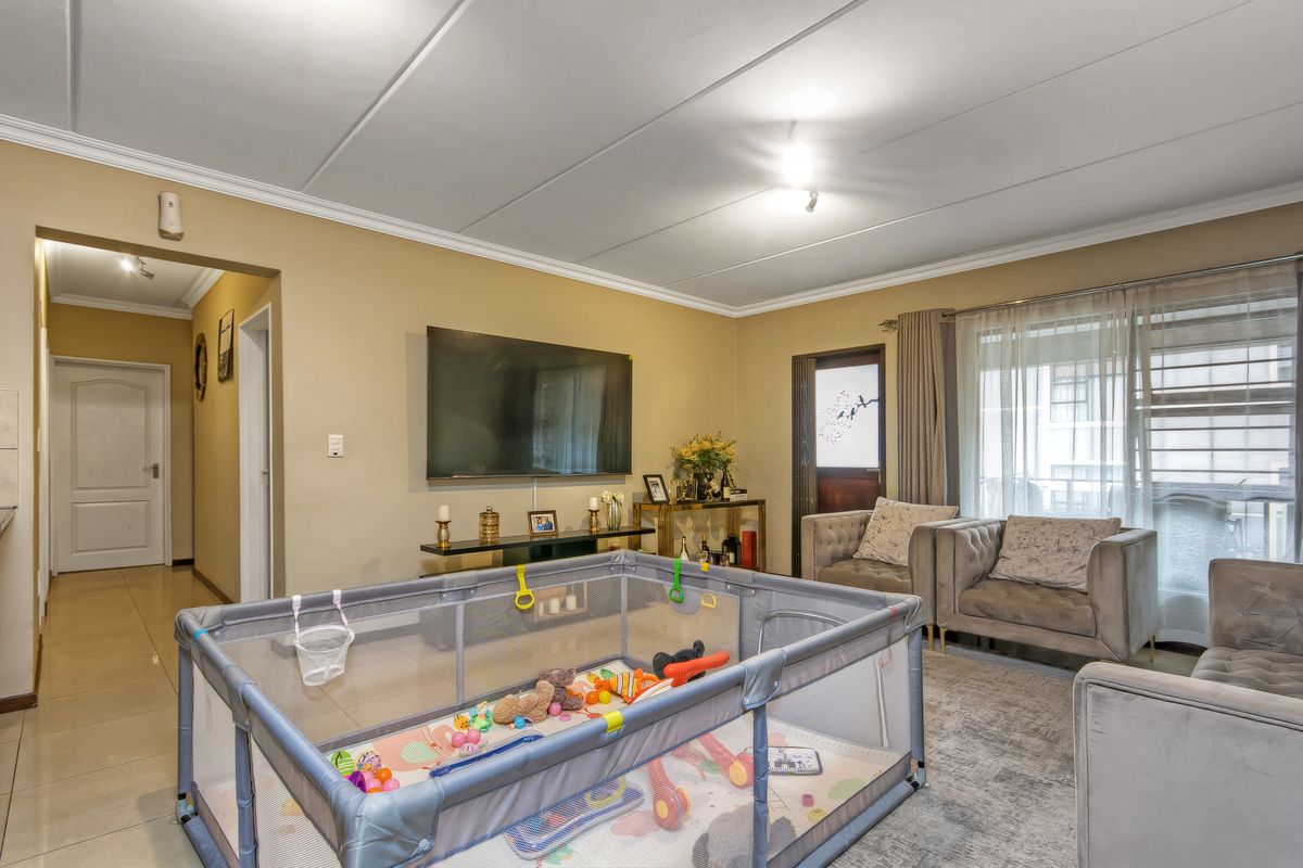 A comfortable living room featuring tiled flooring, coved ceilings, and direct access to an outdoor area through a sliding glass door.