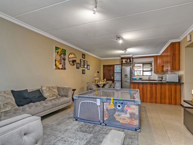 Open-plan living area featuring a functional kitchen with wooden cabinetry, tiled flooring, and a seamless flow between the kitchen and lounge space.