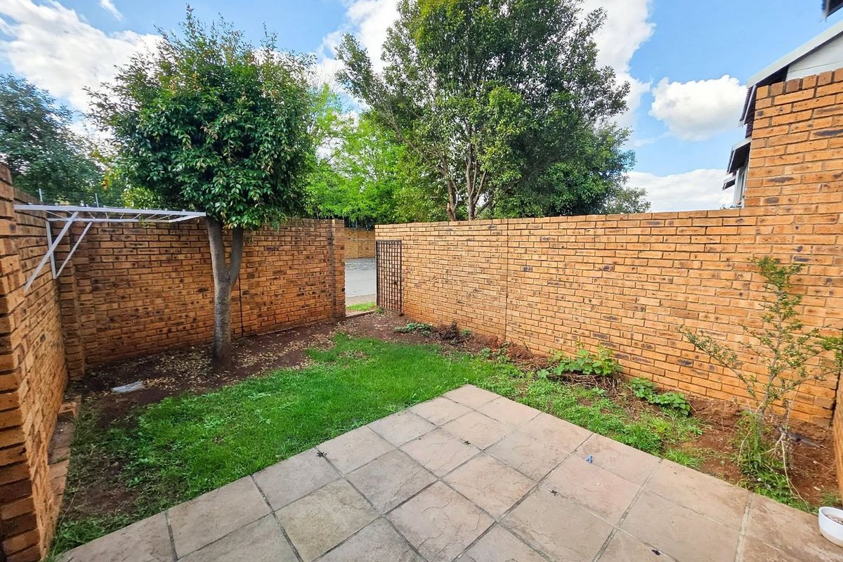 Private rear courtyard featuring a paved patio area, brick boundary walls, and a small garden space with a wall-mounted clothesline.