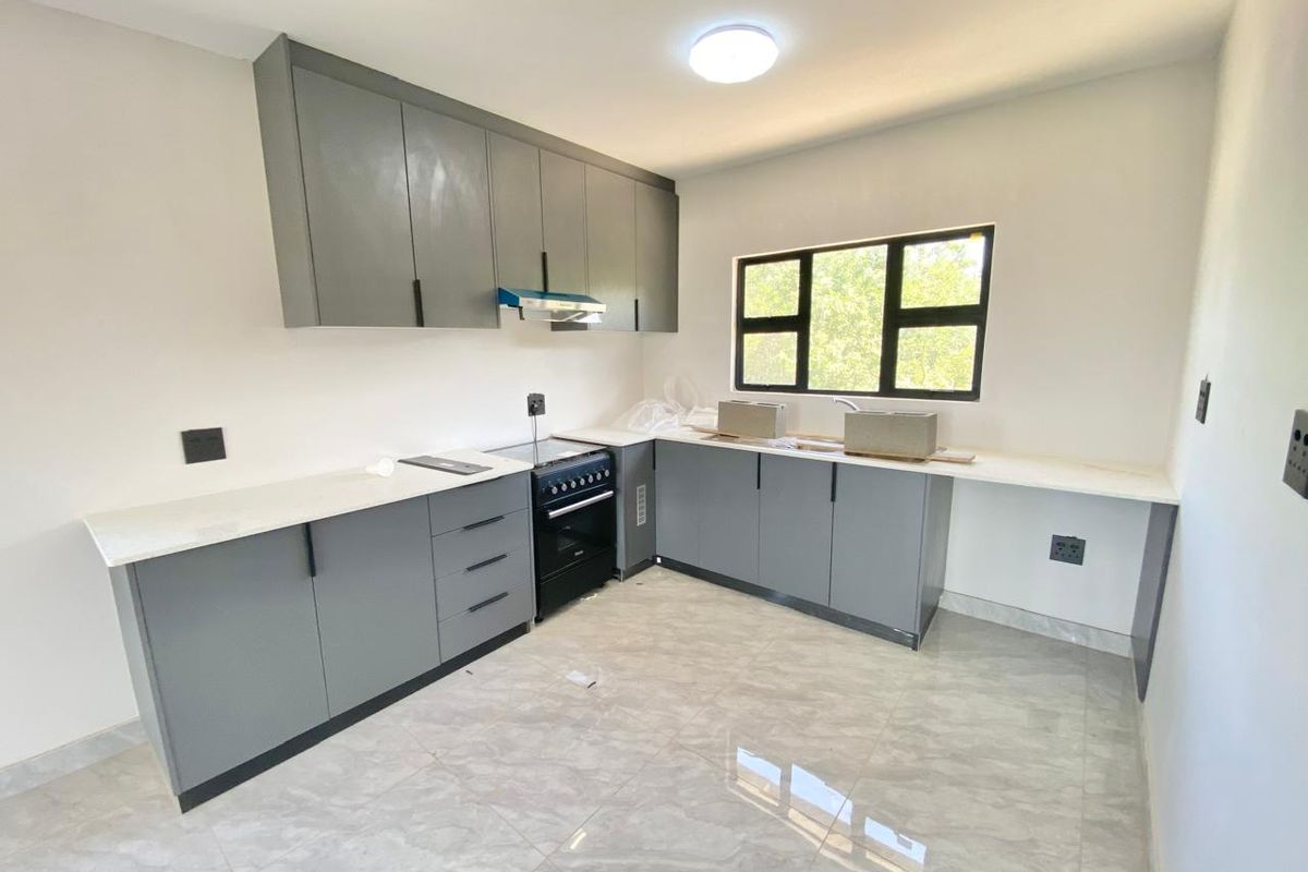 Modern kitchen featuring grey cabinetry, white countertops, tiled flooring, and a built-in stove with an extractor fan.