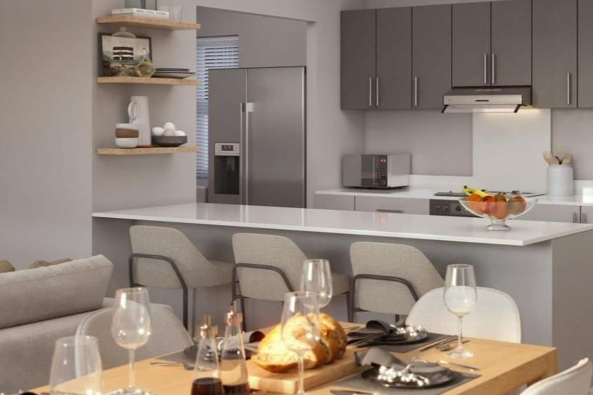 Modern open-plan kitchen and dining area featuring sleek grey cabinetry, stone countertops, integrated appliances, and contemporary track lighting.