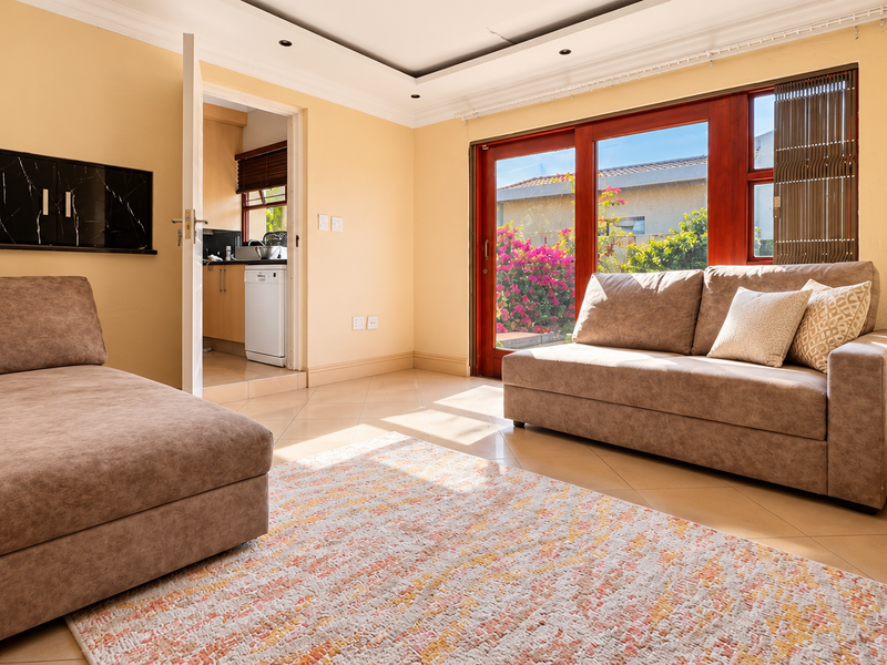 A bright living room featuring tiled floors, coved ceilings, and a sliding glass door providing access to the outdoor area.