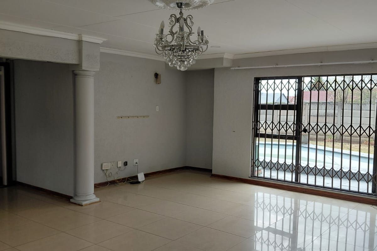 Spacious living area featuring large format floor tiles, a decorative ceiling rose with a crystal chandelier, and direct access to the pool area.