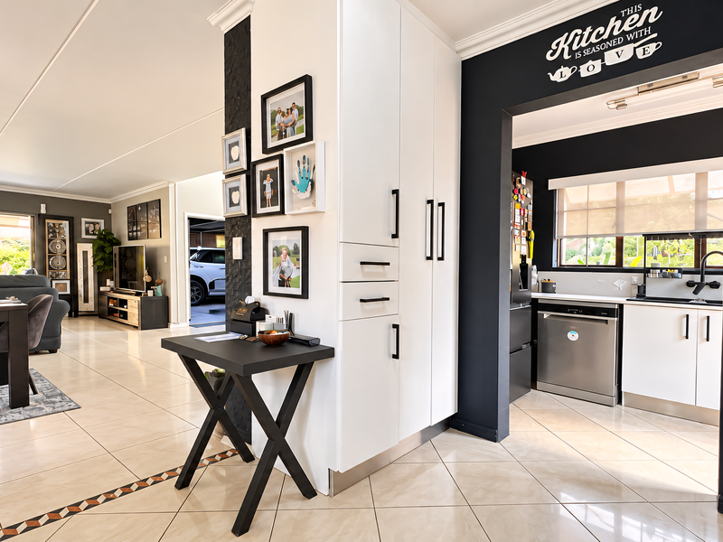 Spacious open-plan living area featuring modern tiled flooring, built-in cabinetry, and a functional kitchen with integrated appliances and contemporary finishes.