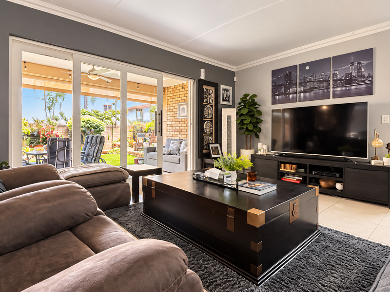 Spacious living room featuring large sliding glass doors that open onto a private patio and garden area, providing excellent natural light.