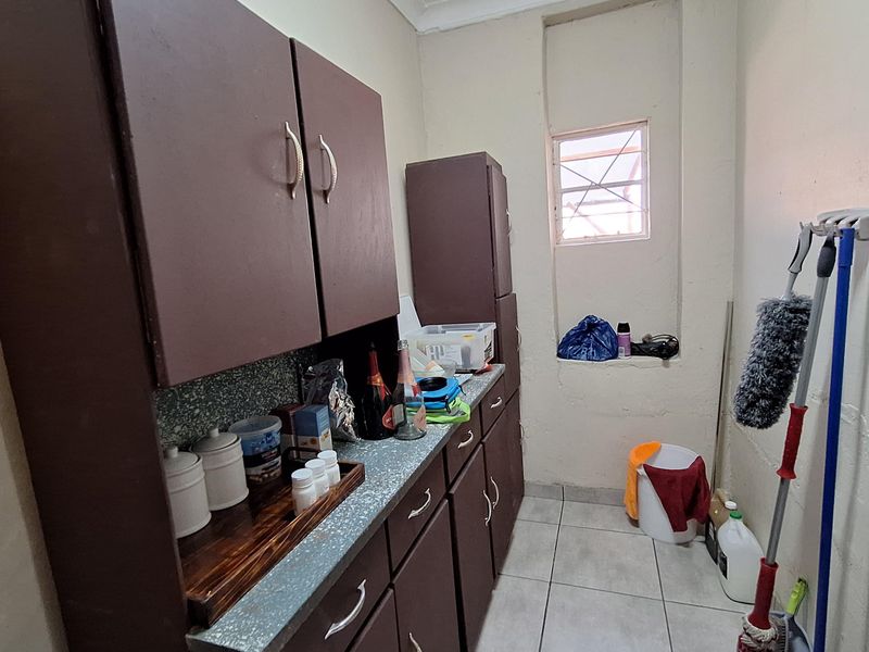 A functional laundry or utility space featuring built-in dark cabinetry, tiled flooring, and a small window for natural light.