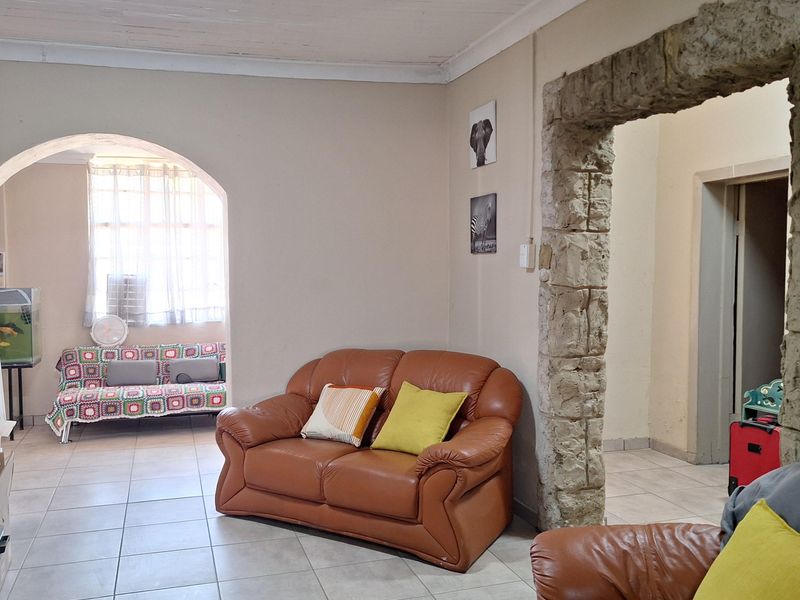 Living area featuring a distinctive stone archway, tiled flooring, and an additional arched alcove space.