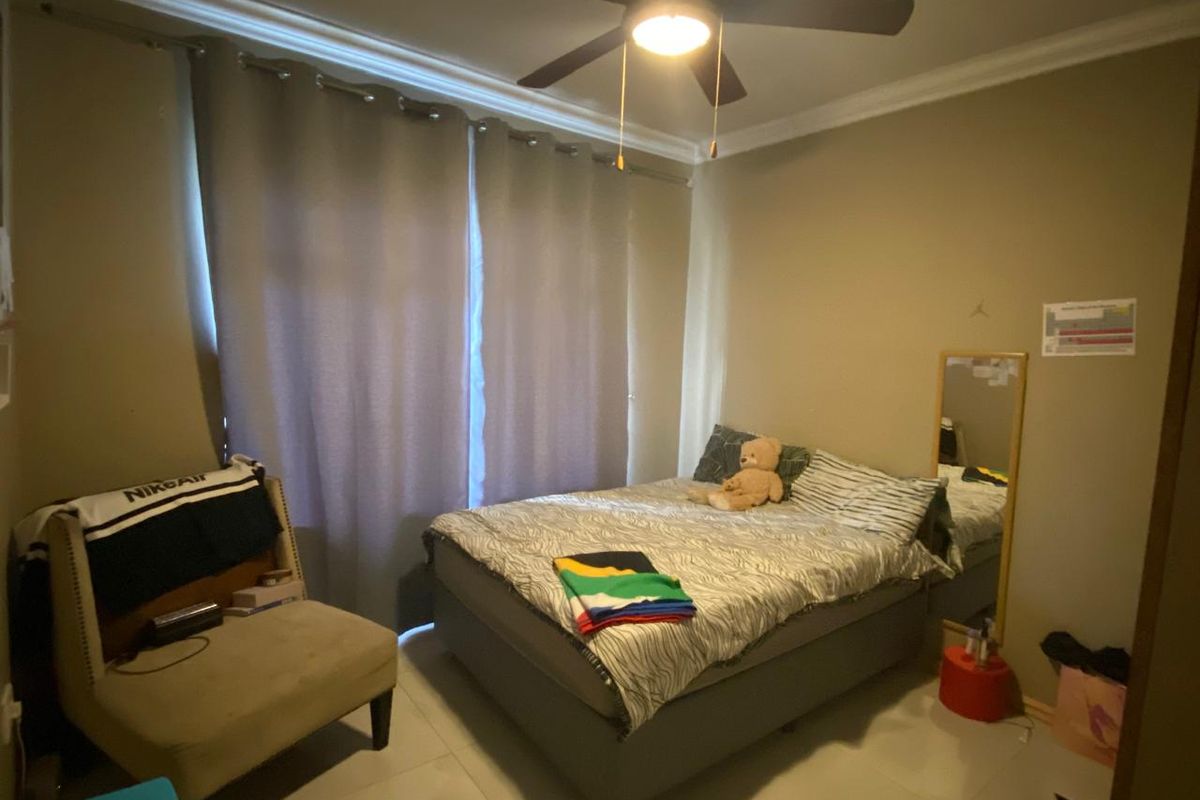 A bedroom featuring tiled flooring, crown molding, and a central ceiling fan with integrated lighting.