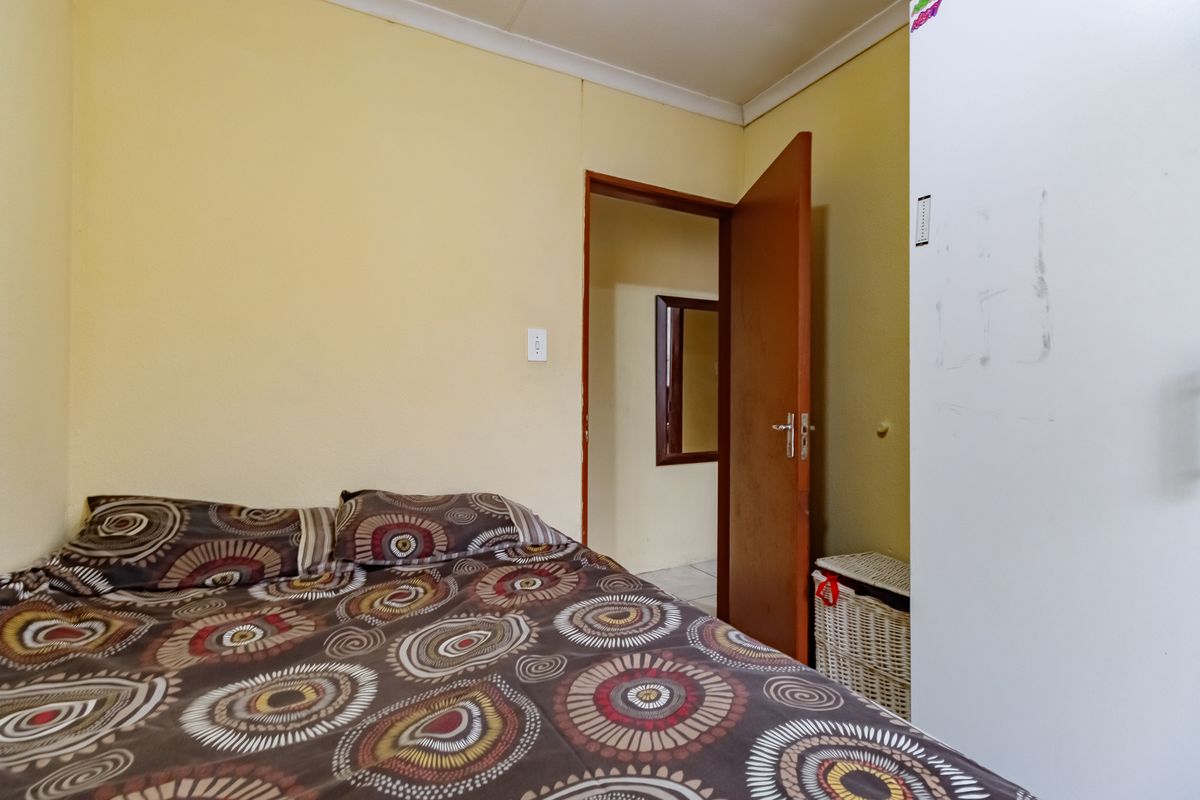 A compact bedroom featuring yellow walls, a built-in cupboard, and a doorway leading to an adjacent space.