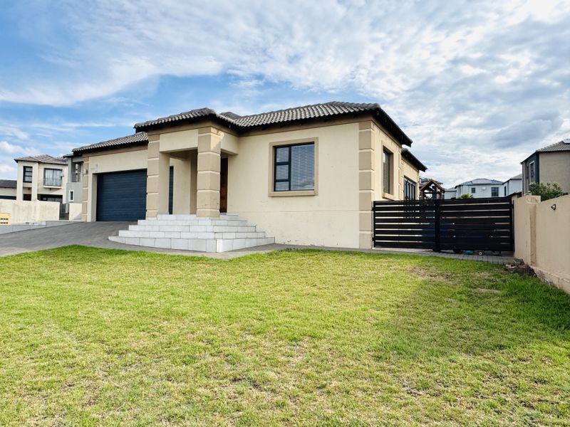 A well-maintained single-story residential home featuring a tiled roof, double garage, paved driveway, and a neat front lawn with secure boundary fencing.