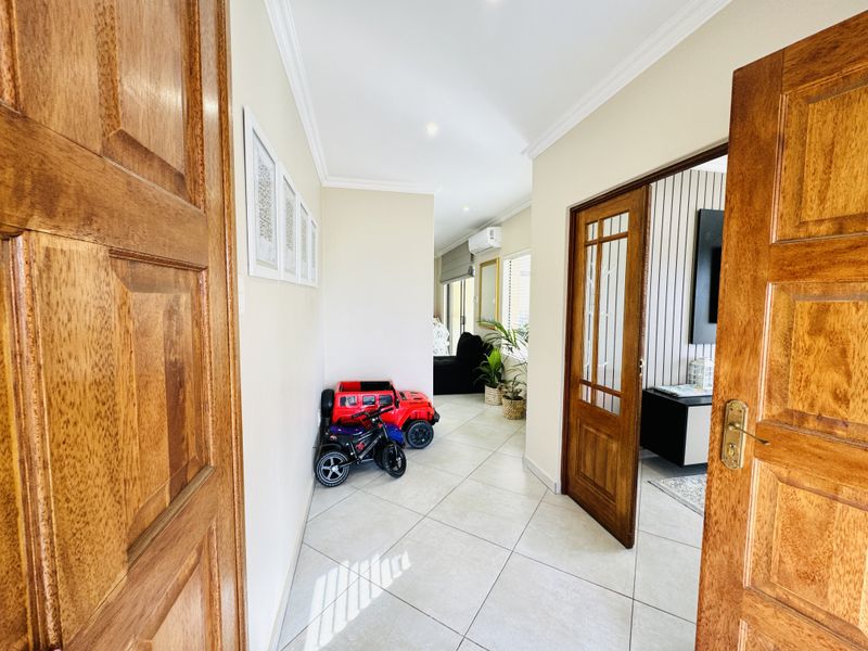 A bright, tiled hallway featuring wooden door frames and coved cornicing, providing access to adjacent living spaces.