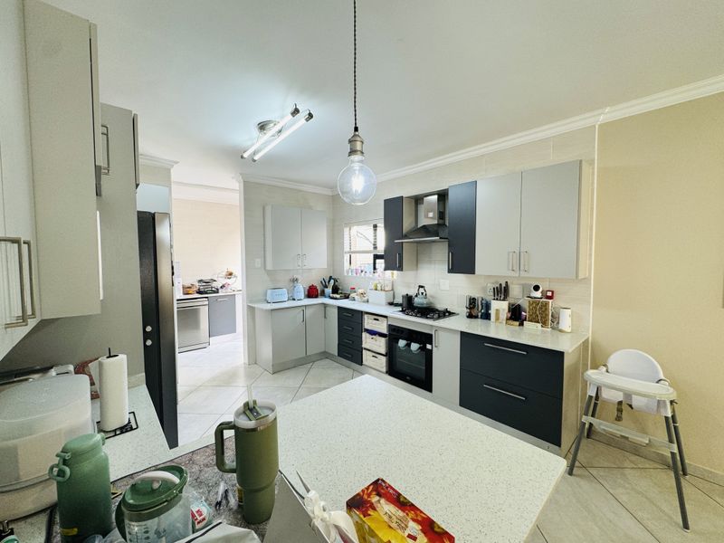 Modern kitchen featuring two-tone cabinetry, stone countertops, built-in oven, gas hob, and an open-plan layout connecting to a scullery area.