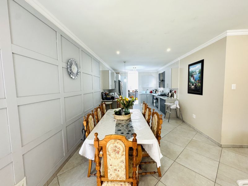 Spacious open-plan dining and kitchen area featuring modern cabinetry, tiled flooring, and decorative wainscoting, creating a functional and cohesive living space.