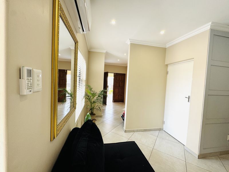 A well-maintained hallway featuring tiled flooring, recessed downlighting, crown molding, and built-in cabinetry, providing a clean and functional transition space.