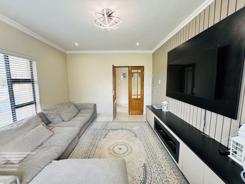 A well-maintained living room featuring modern slatted wall paneling, a built-in media console, and neutral finishes with ample natural light.