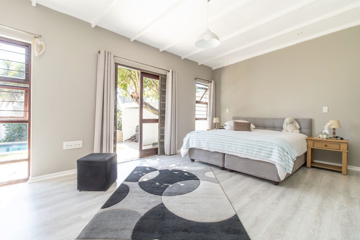 Spacious bedroom featuring light laminate flooring, exposed beam ceiling, and direct access to the outdoor patio area through sliding glass doors.
