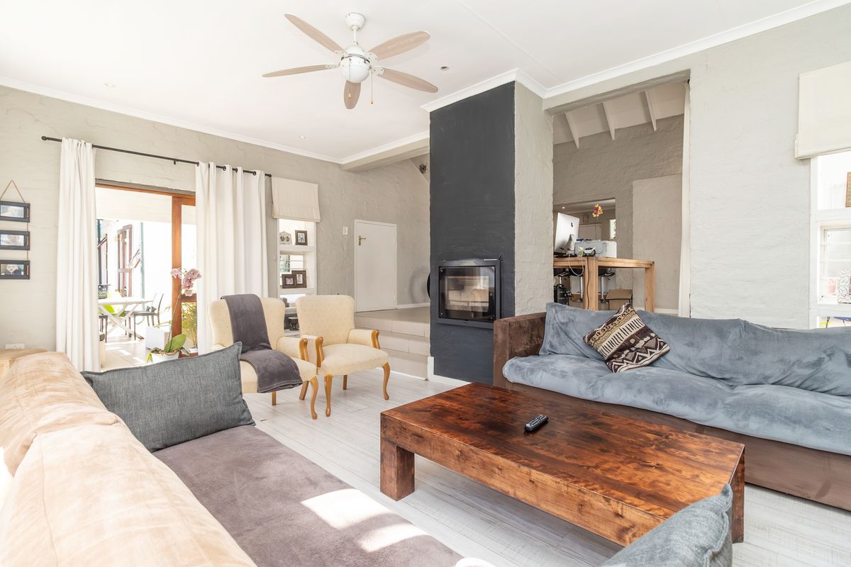 Spacious living room featuring a central built-in fireplace, ceiling fan, and direct access to an outdoor patio area through sliding glass doors.