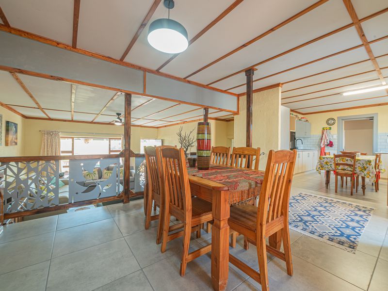 Open plan dining and kitchen area featuring tiled floors, exposed beam ceilings, and a decorative balustrade overlooking the lower living space.
