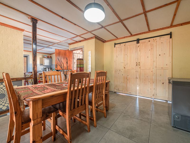 Dining area featuring tiled flooring, exposed beam ceiling, and wooden sliding barn doors, providing a rustic aesthetic with potential for modern updates.