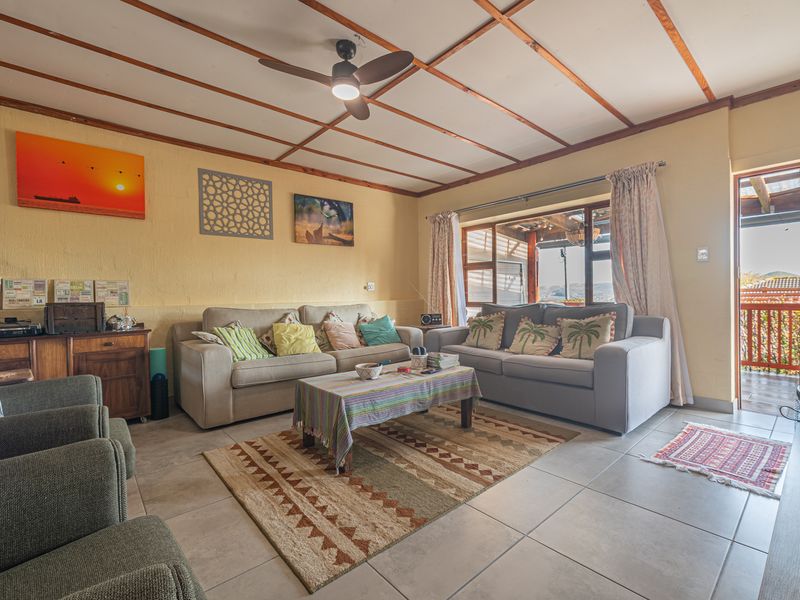 A comfortable living room featuring exposed timber ceiling beams, a ceiling fan, and tiled flooring, with direct access to an outdoor patio area.