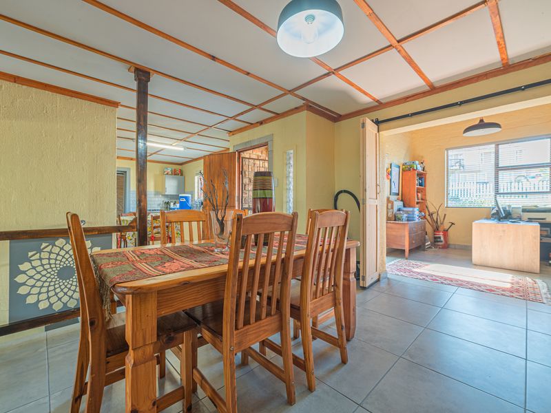 Open plan dining area featuring tiled floors and an exposed beam ceiling, with a sliding barn door leading to an adjacent room.