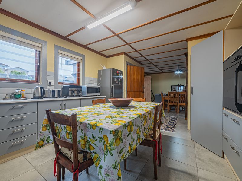 A functional kitchen featuring tiled flooring, built-in cabinetry, and an integrated oven, with an adjacent dining area visible in the background.