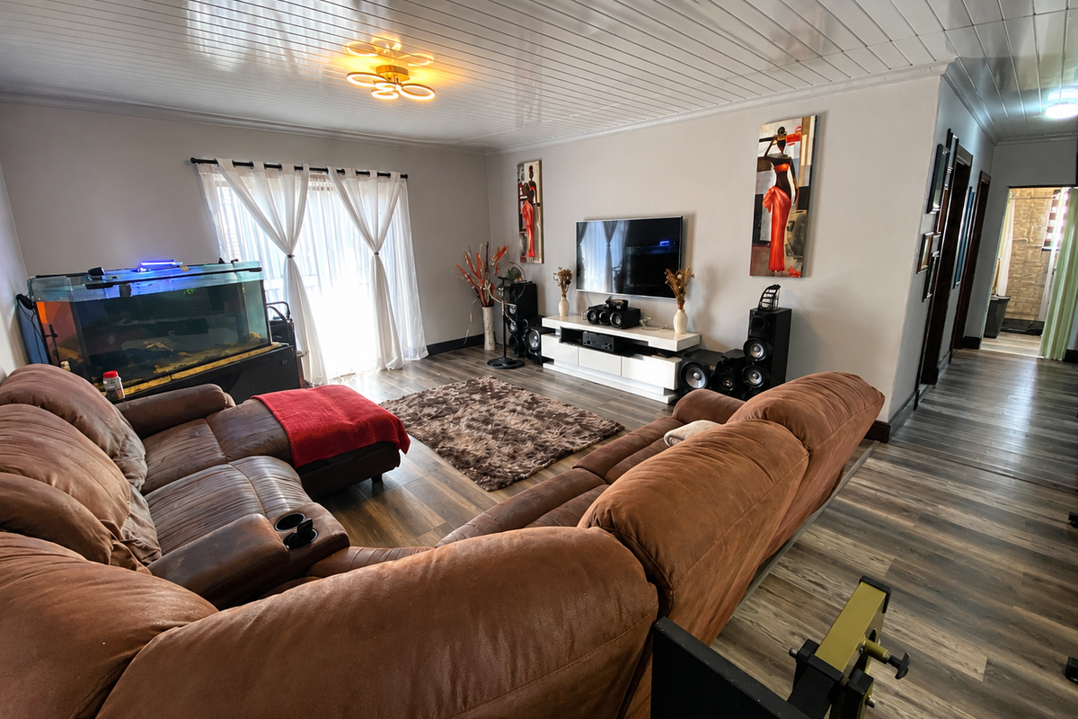 Spacious living room featuring wood-look laminate flooring, a tongue and groove ceiling, and a sliding glass door providing natural light.