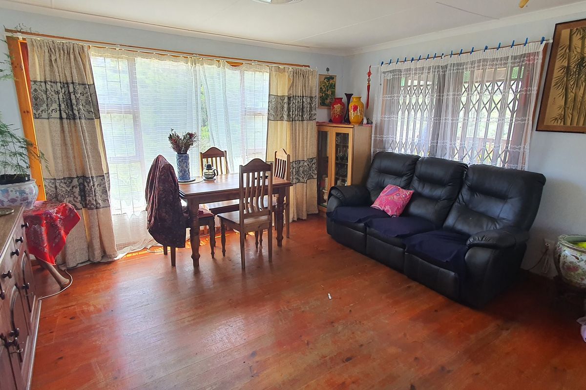 A living room featuring timber flooring, large windows with security gates, and neutral wall finishes.